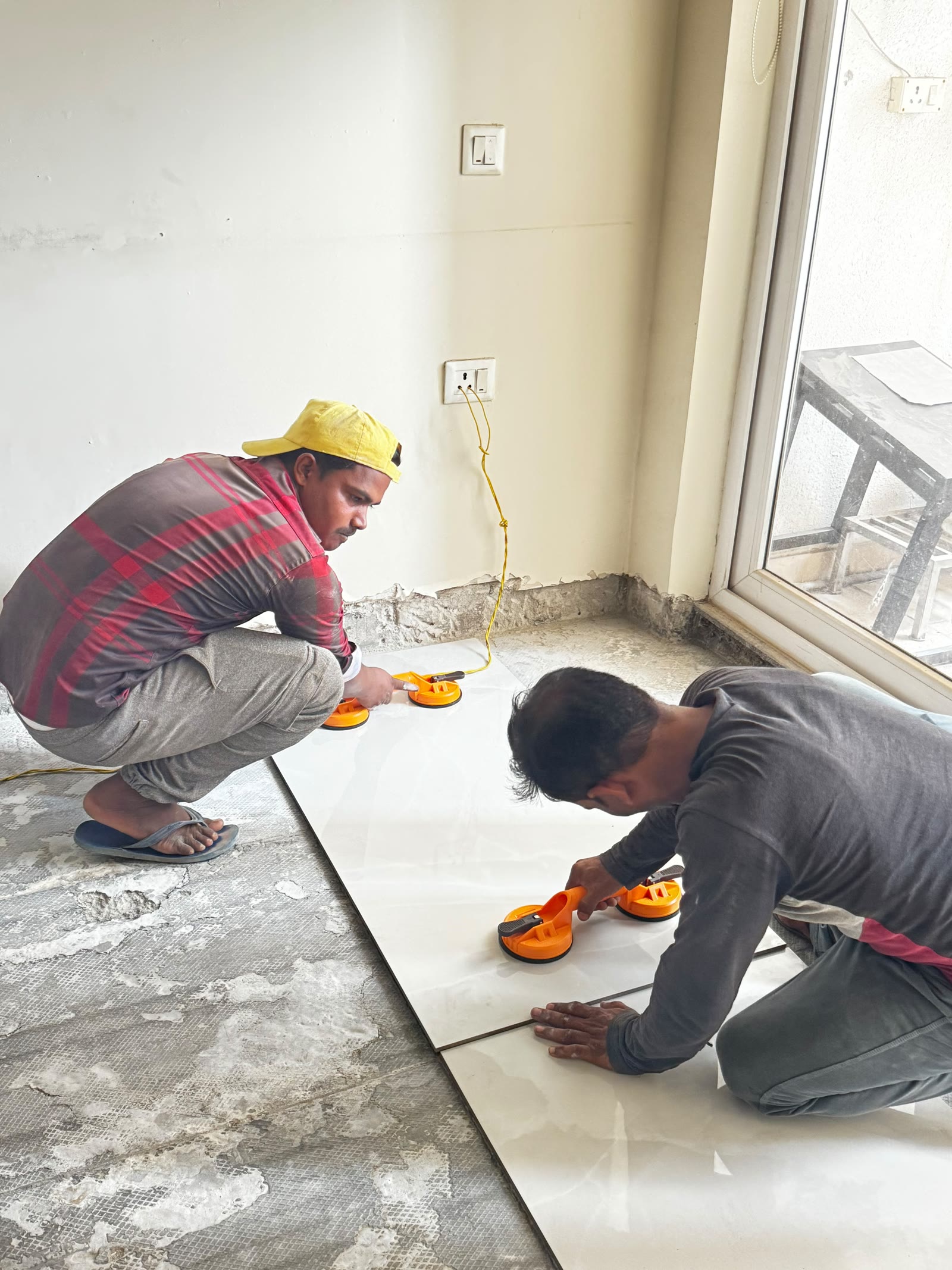 Craftspeople aligning large-format floor tiles with suction lifters